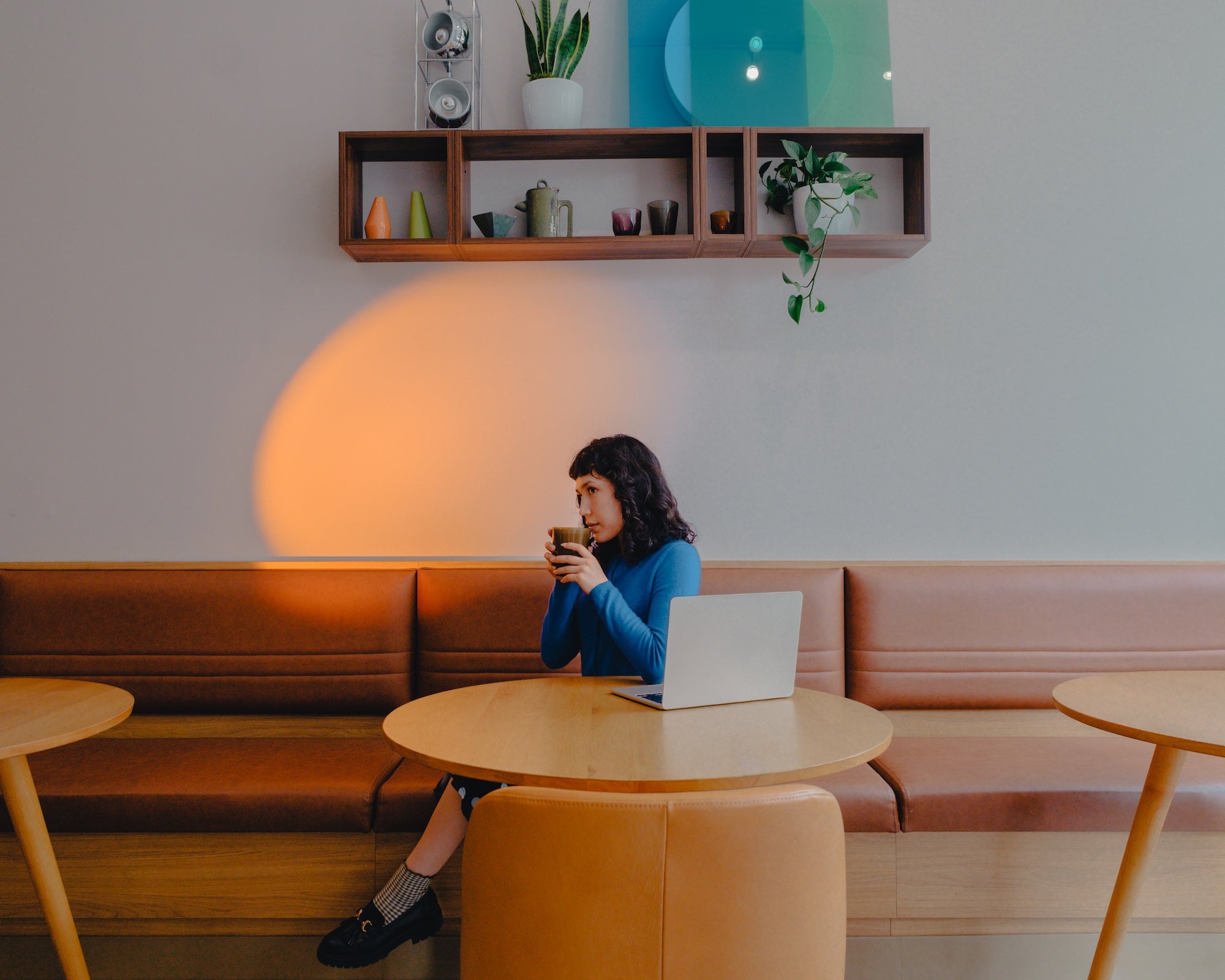 Atmos Coffee interior with warm leather seating, wood tables and colorful lighting