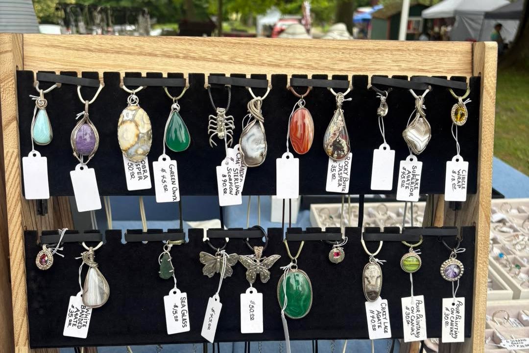 Handmade pendant necklaces on display at a vendor table at the Peninsula Flea at Heritage Farms in Peninsula
